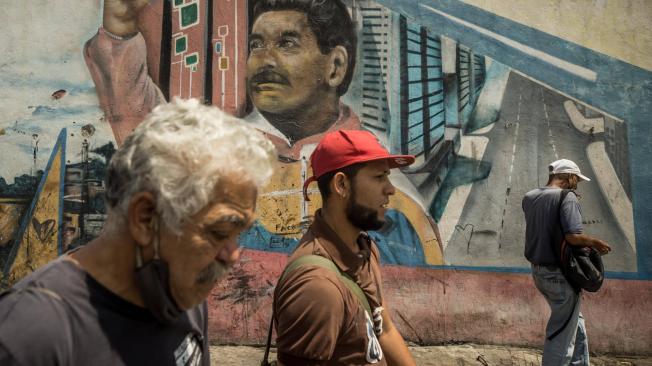 Varias personas caminan frente a un graffiti con la imagen del presidente de Venezuela, Nicolás Maduro. Foto: EFE/Miguel Gutiérrez