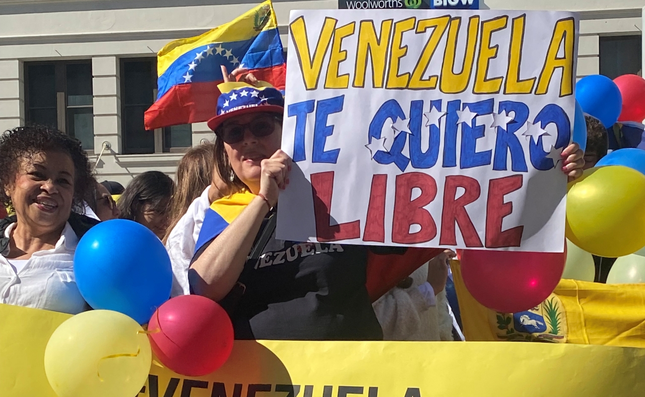 Venezolanos sostienen banderas y carteles durante una protesta este sábado en el centro de Sidney. Foto: EFE.