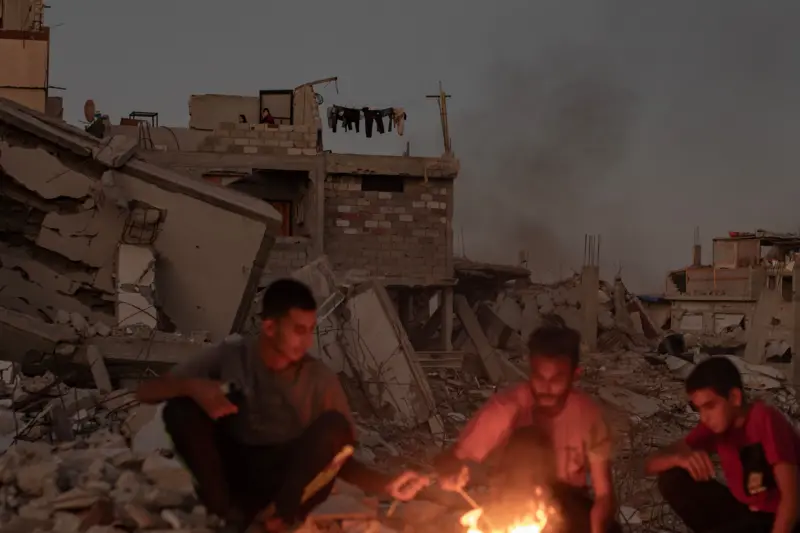 Palestinos sentados entre los escombros de su casa destruida en Gaza