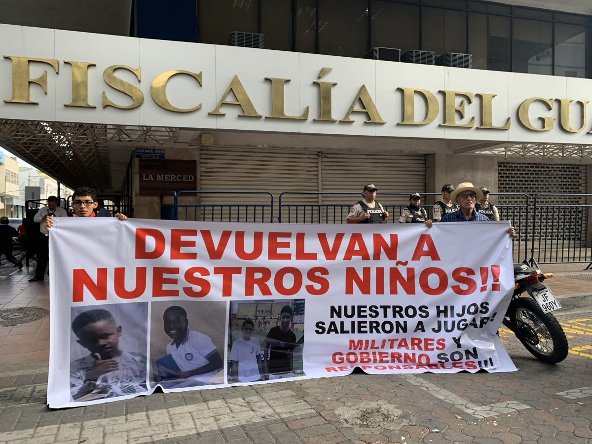 Fotografía del 23 de diciembre de 2024 que muestra dos personas sosteniendo un cartel en los exteriores de la Fiscalía Provincial del Guayas con el mensaje devuelvan a nuestros niños, en alusión a los cuatro menores desaparecidos el 8 de diciembre en Guayaquil. Foto: Efe.